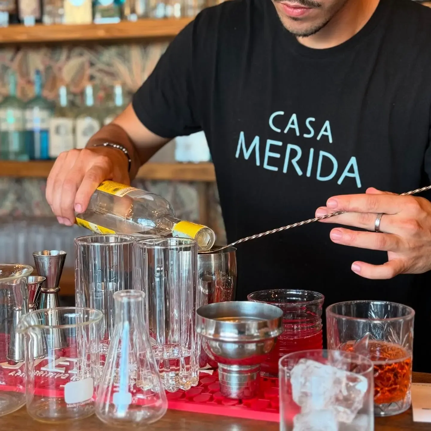 Barista di Casa Merida che prepara un cocktail dietro al bancone con strumenti professionali