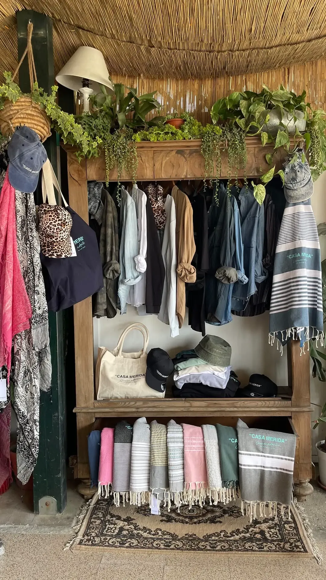 Boutique interna con espositori in legno, abbigliamento e accessori con logo Casa Merida