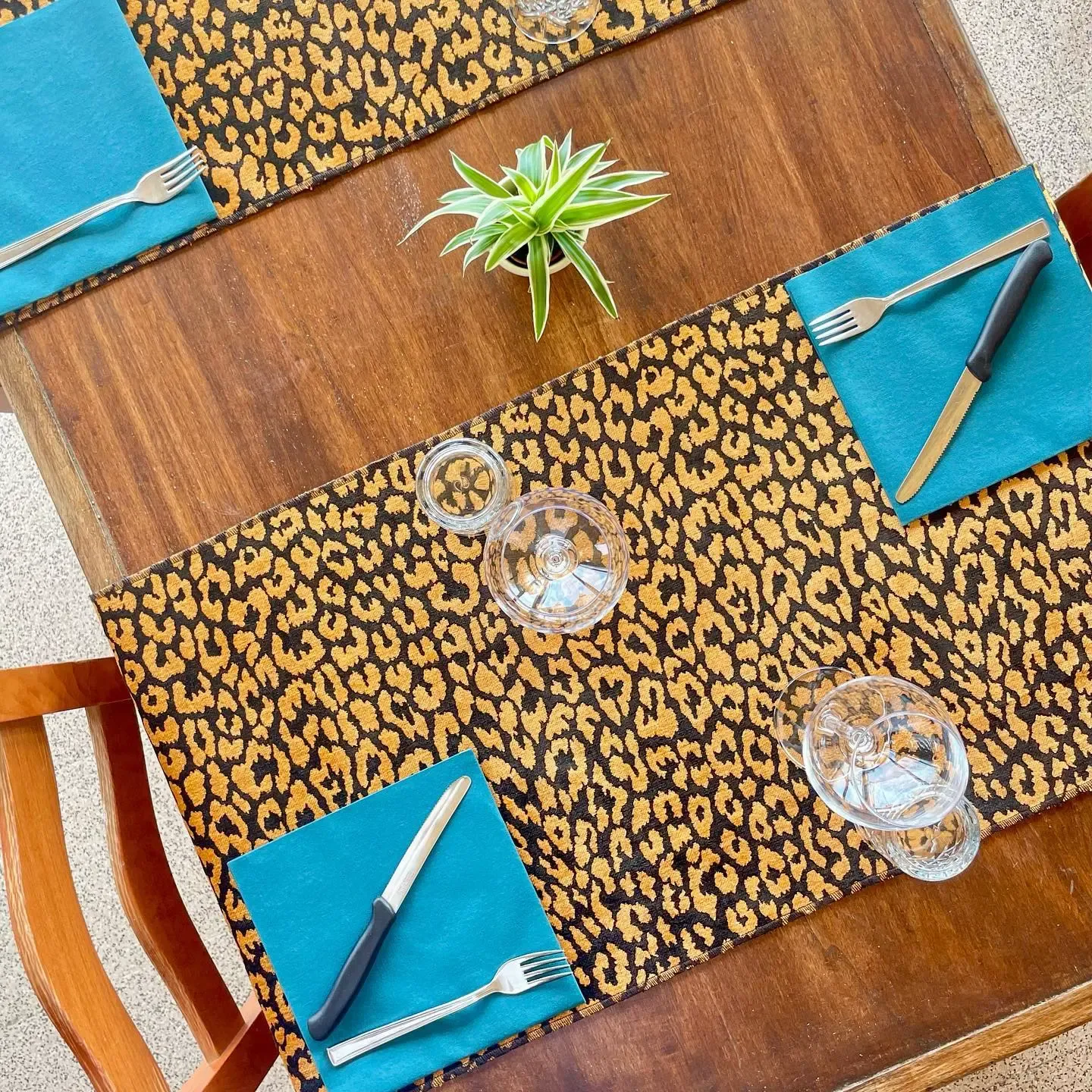 Tavolo apparecchiato con placemat leopardato, tovaglioli blu e bicchieri di cristallo