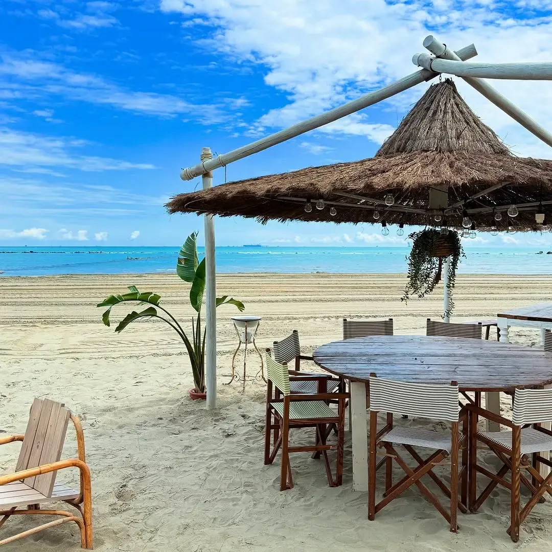Tavolo rotondo sotto palapa in paglia con vista sul mare turchese