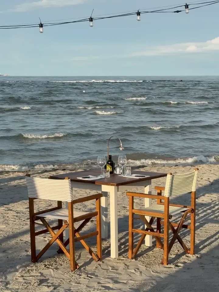 Cena romantica per due sulla spiaggia con lume di candela e calici di vino