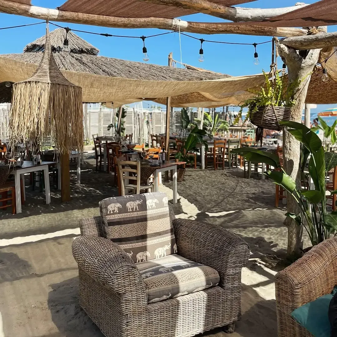 Area lounge con poltrone in vimini, cuscini con motivi elefante e palapas